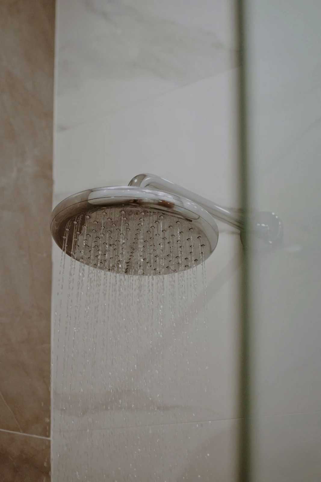 Close-up of a modern showerhead with water flowing indoors. Ideal for lifestyle and home decor use