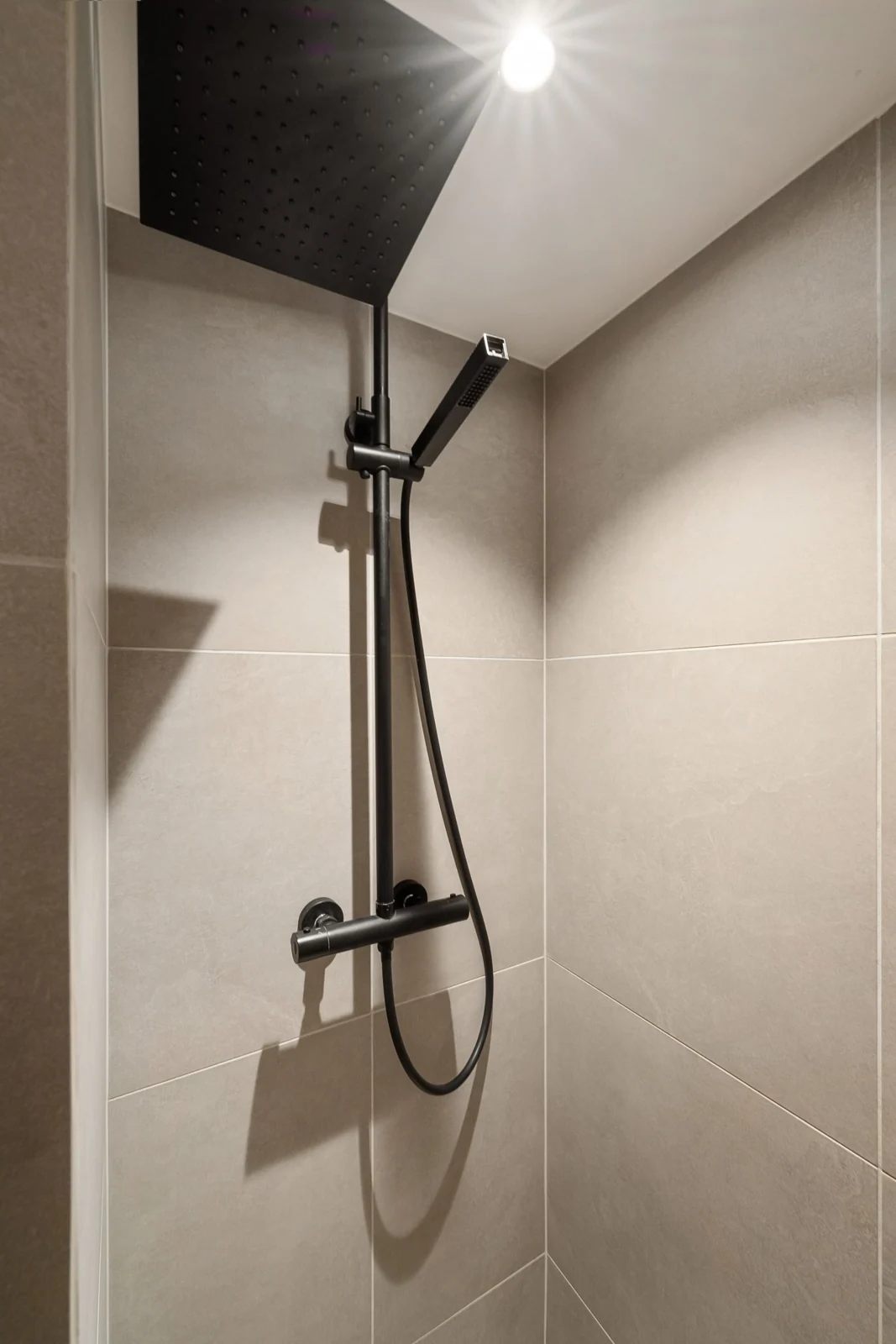 Contemporary shower design featuring sleek black fixtures under soft overhead lighting