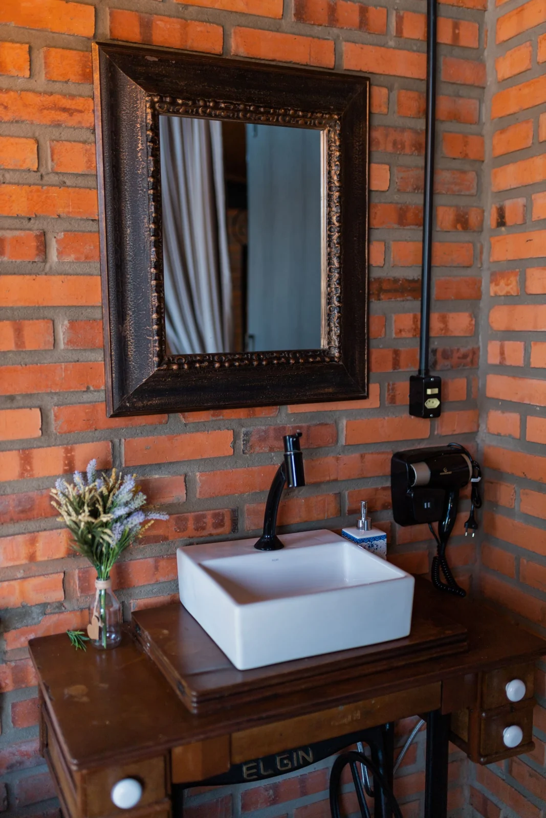 Bathroom basin against an exposed brick wall