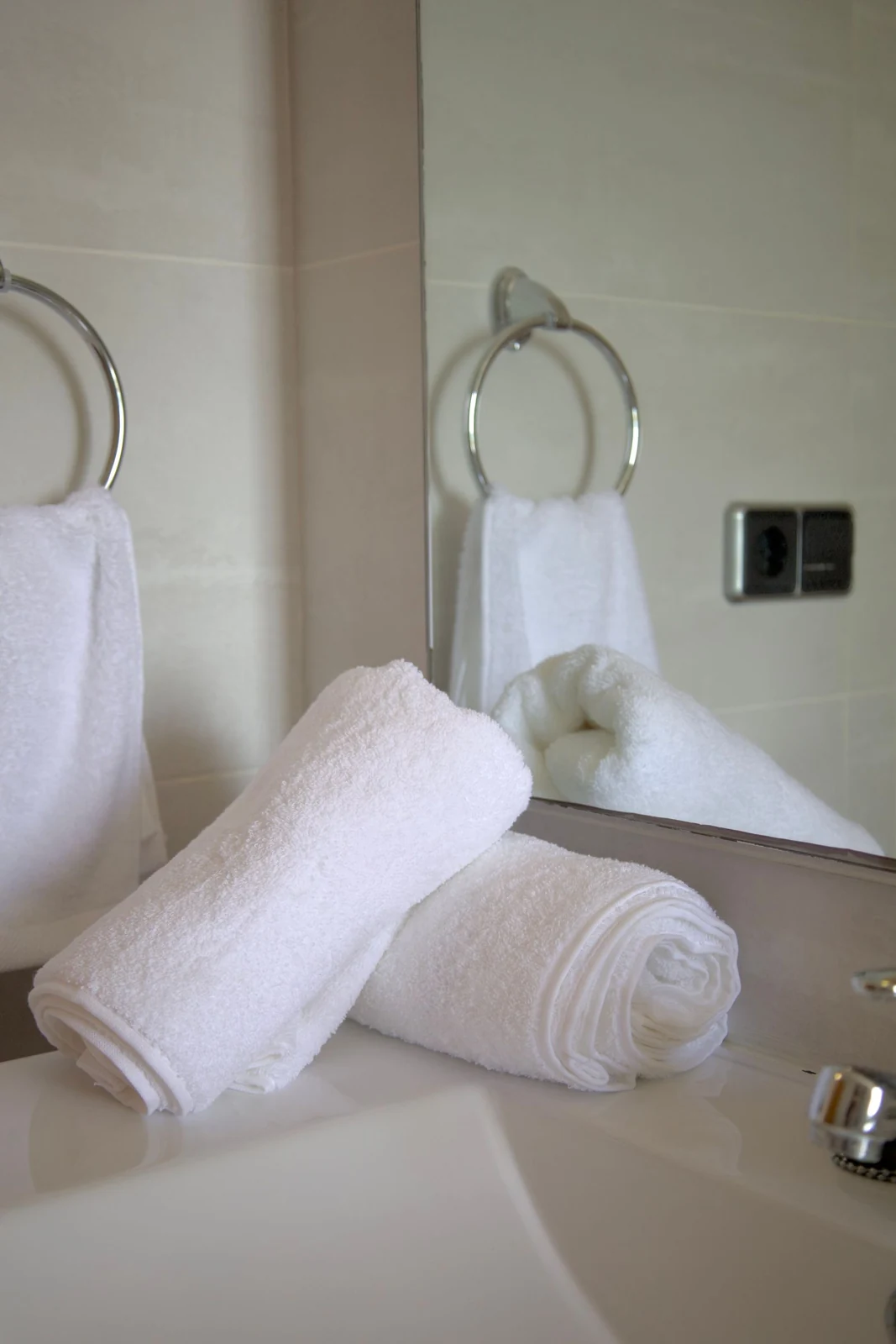 Folded bathroom towels beside a basin