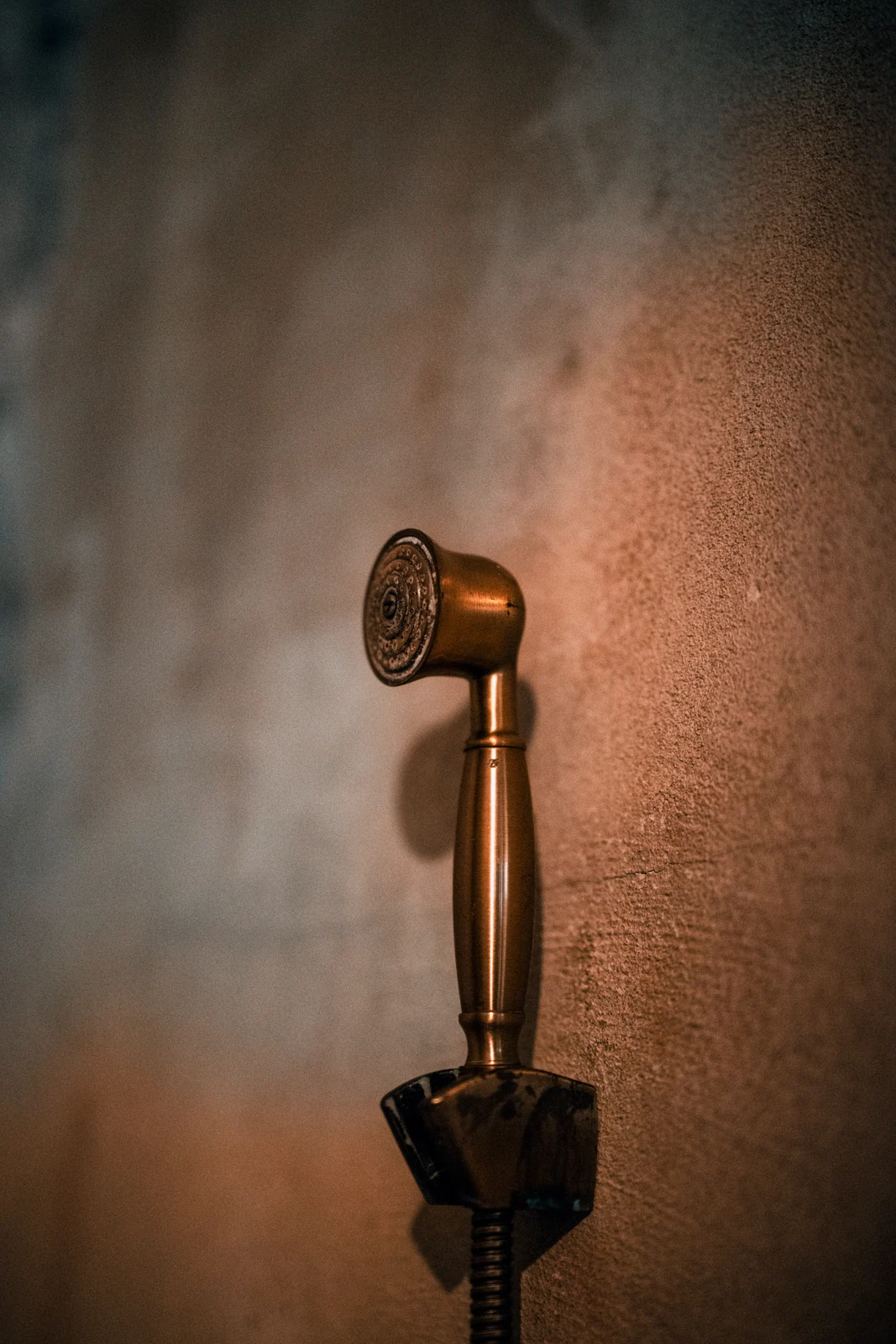 Close-up of a vintage brass shower head against a textured wall in Bangkok, Thailand