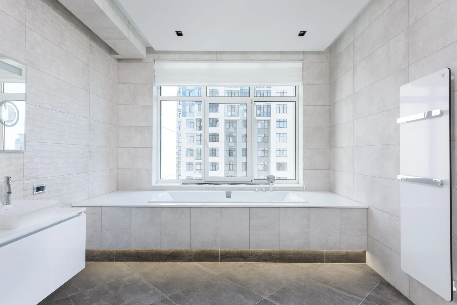 Interior of modern light bathroom with tiled walls and white sink against mirror in daylight
