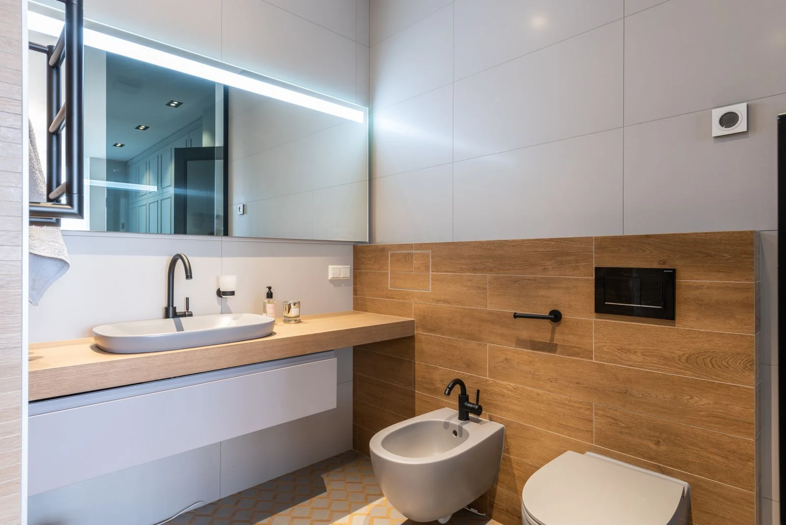 Interior of contemporary stylish wash room with light walls with wooden elements and white toilet and sink placed in modern apartment