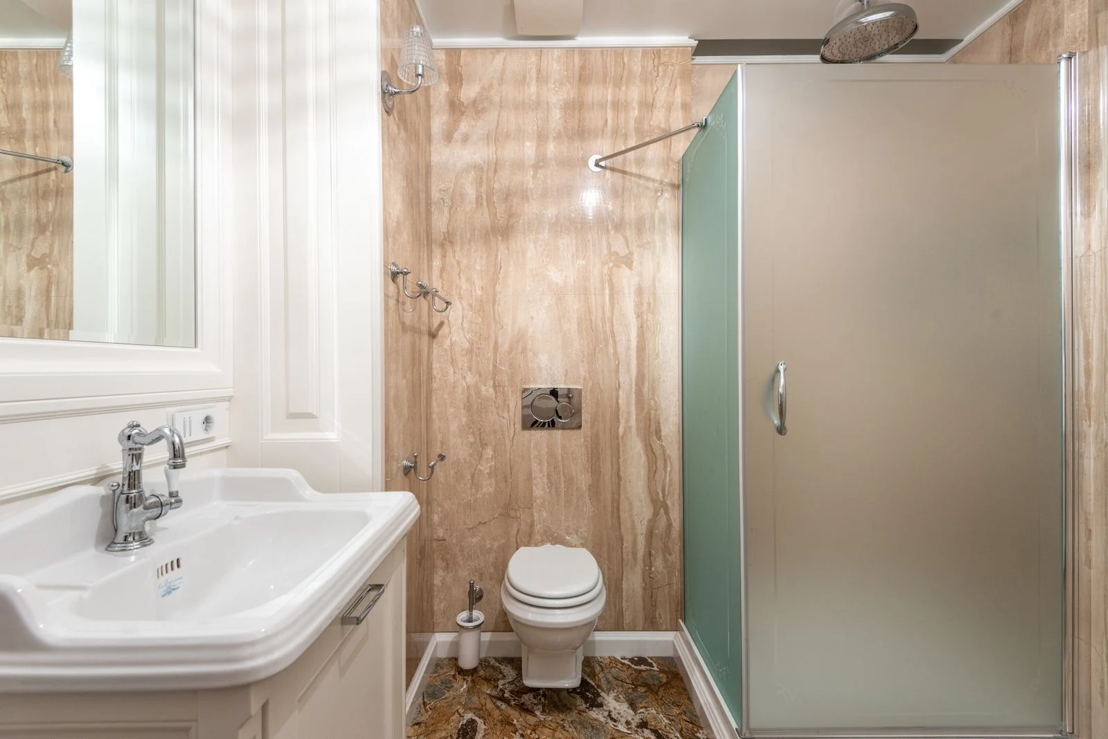 Interior of bathroom with wall mounted toilet and shower cabin at tiled wall near clean sink under bright lighting