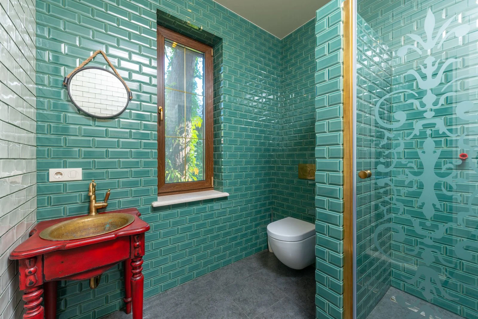 Modern bathroom with green tiled walls, gold fixtures, and elegant decor