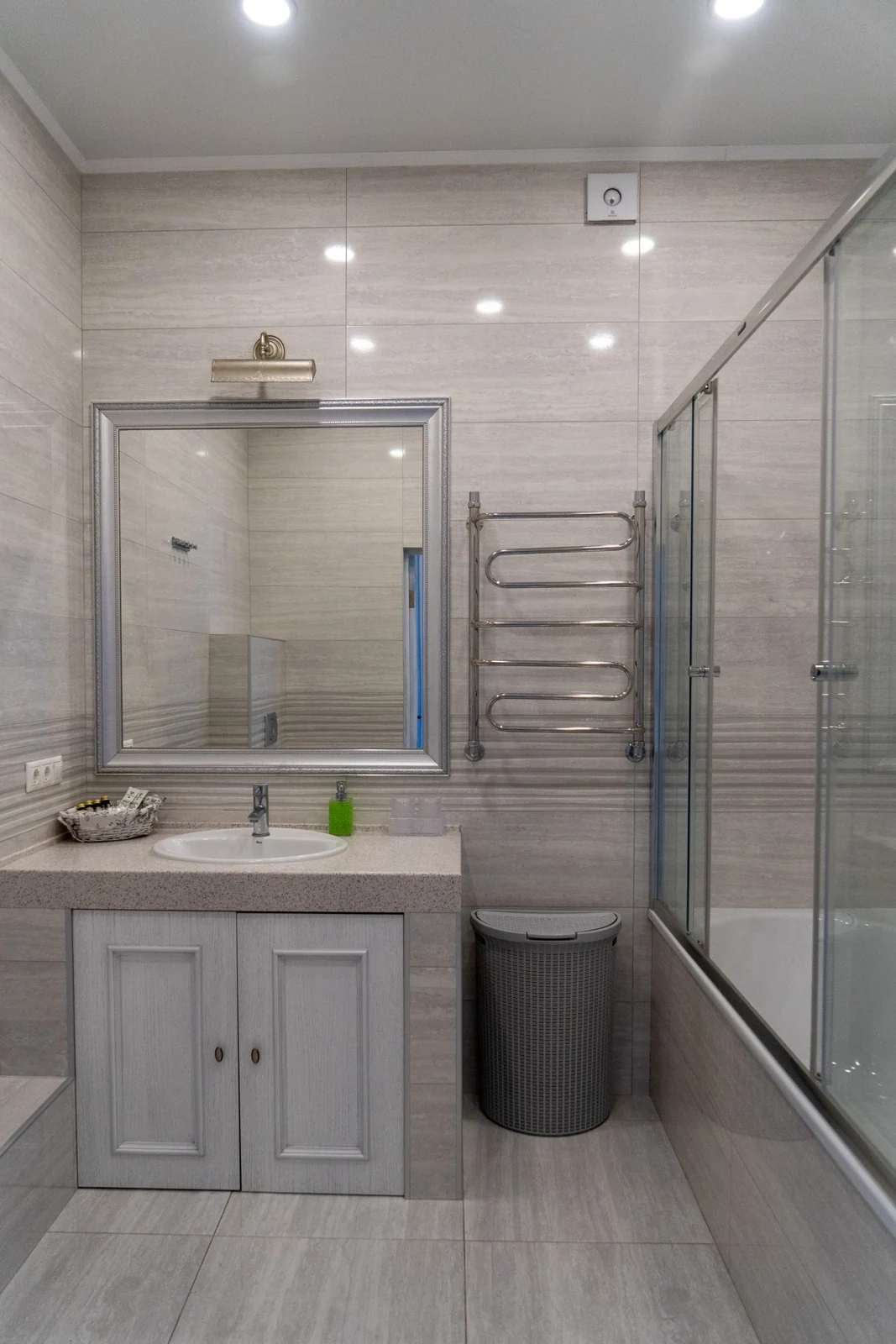 Elegant bathroom featuring a large mirror, glass shower, and modern fixtures in a minimalist style